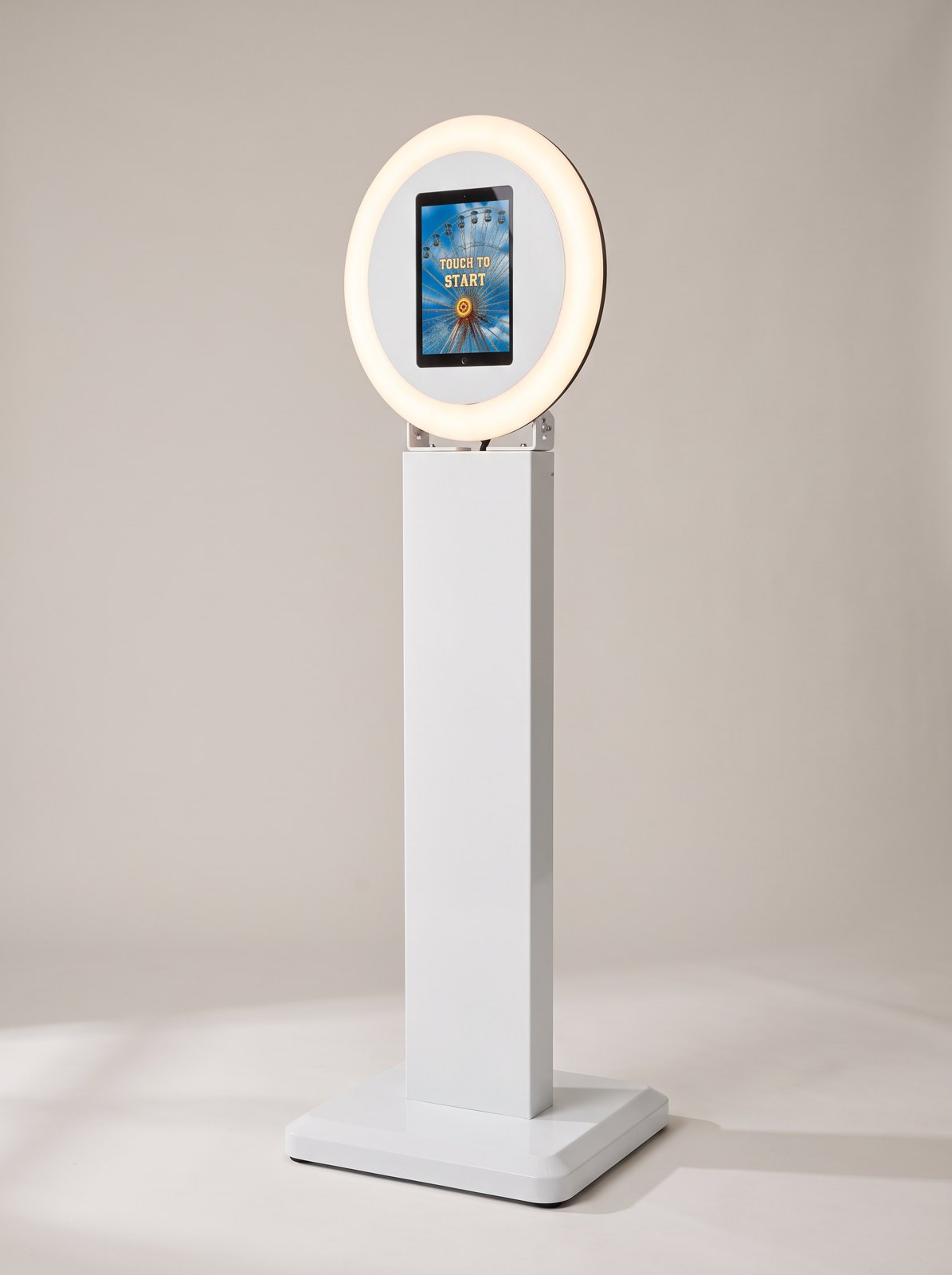 The complete Bergen Photobooth: a white pedestal on a square base with a lit ring light and touch screen on top, on a studio background